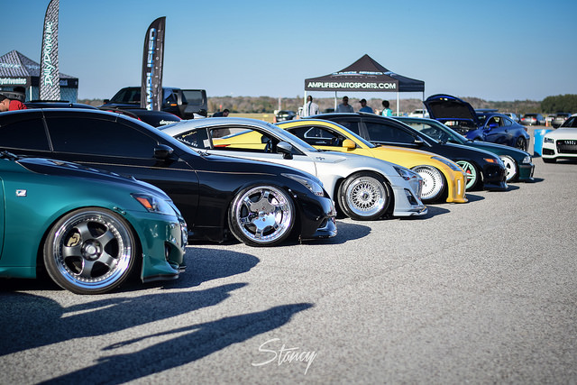 Lineup of customized cars at an auto show, featuring various models and colors