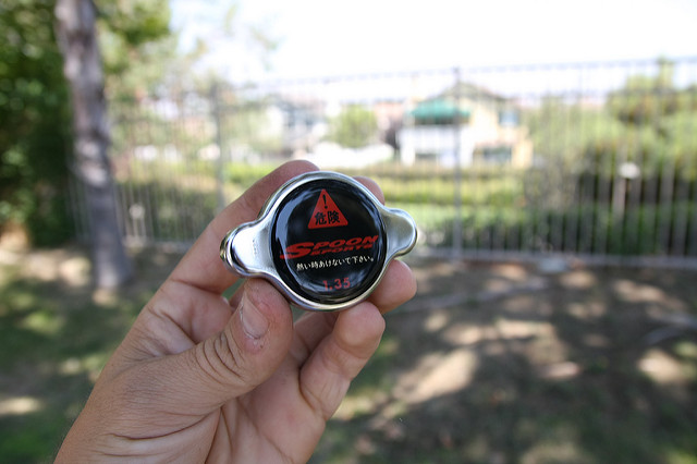 close up image of a person holding a Spoon sports radiator cap outdoors, radiator cap, automotive part