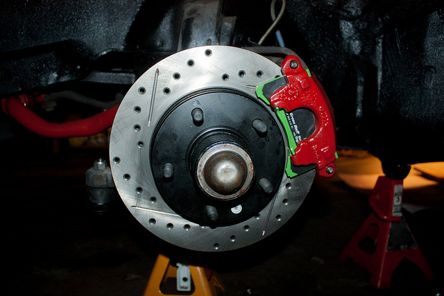 Close-up of car brake rotor and red caliper, highlighting brake system maintenance and repair