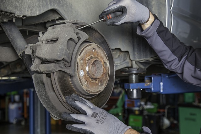 Mechanic performing brake repair on a car, focusing on the brake disc and caliper
