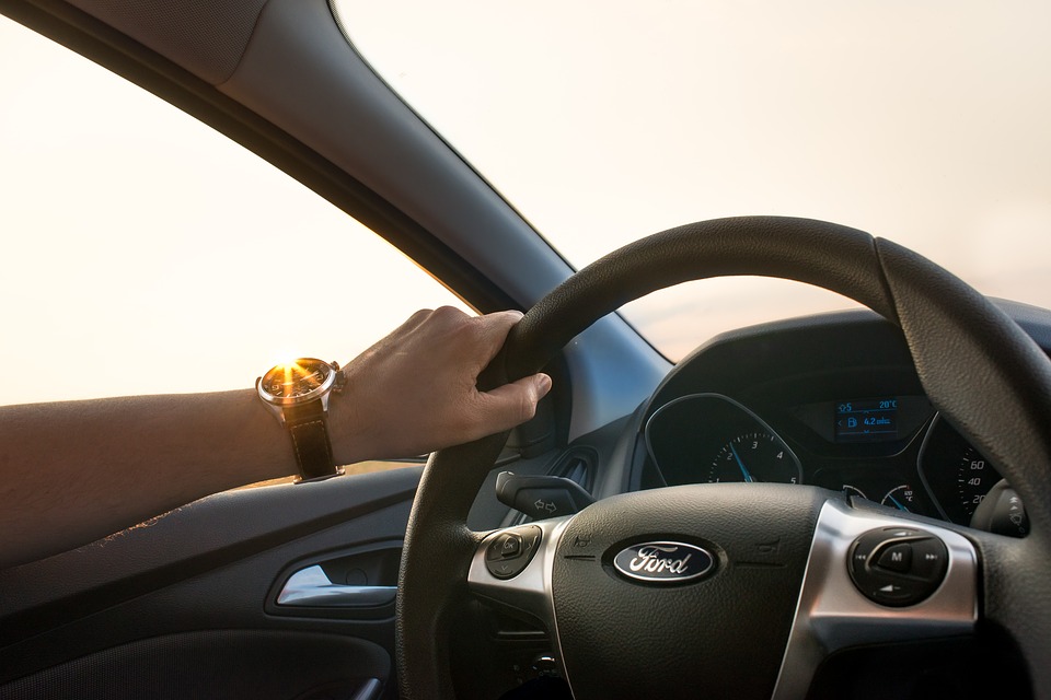 left hand on steering wheel of Ford car