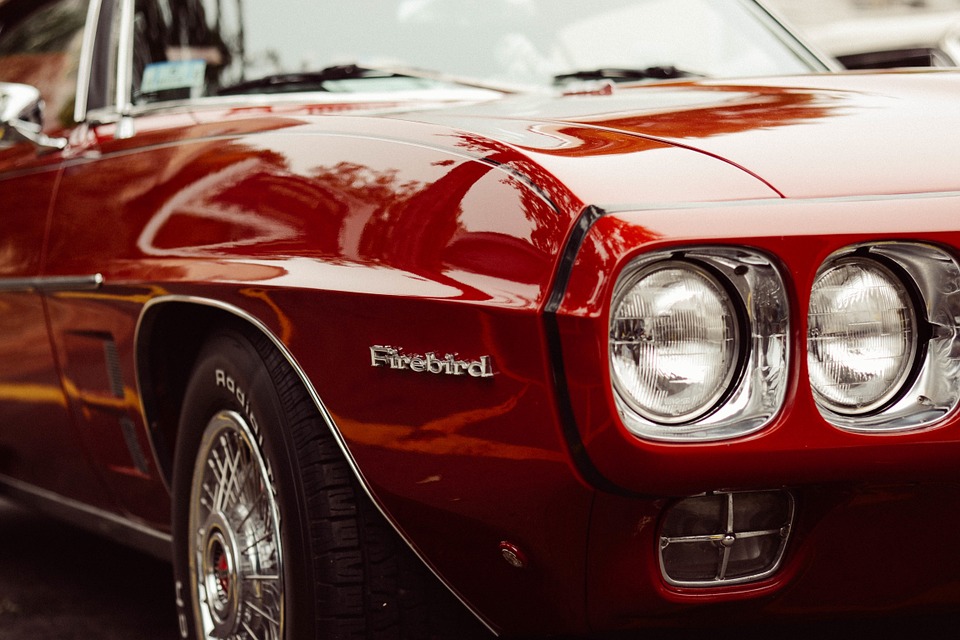 Close-up of red classic Pontiac Firebird car front with chrome details and headlights