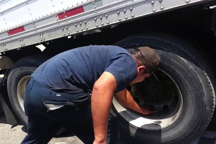 truck driver checking tire pressure