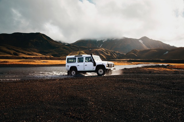 Land Rover Defender crossing a creek in a mountainous landscape, off-roading, SUV, foggy mountains