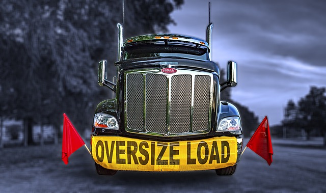 Front view of a large truck with an "Oversize Load" sign and red flags on a rural road Front view of a large truck with an "Oversize Load" sign and red flags on a rural road