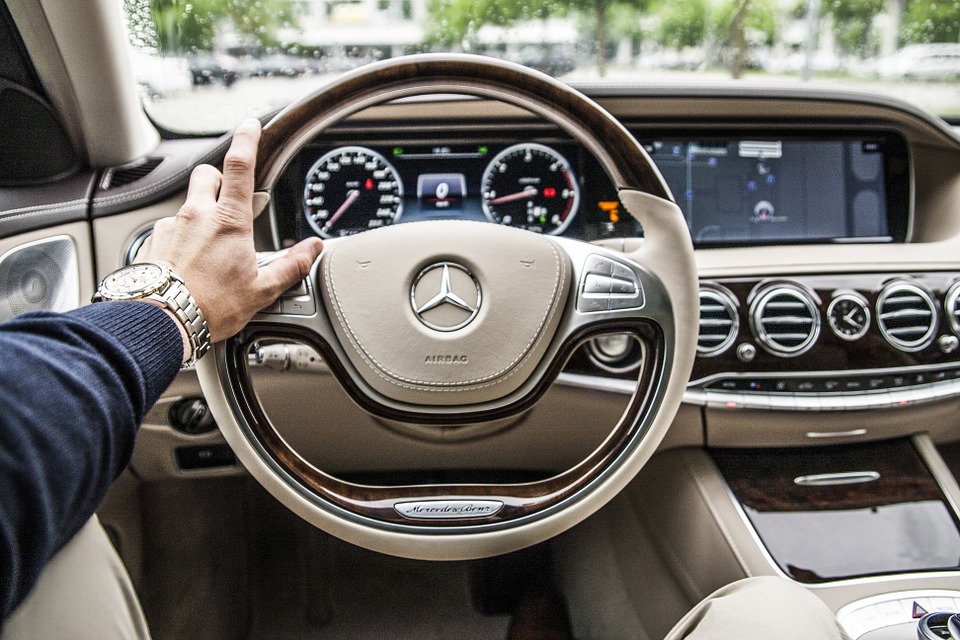 view of car dashboard with man's arm on steering wheel